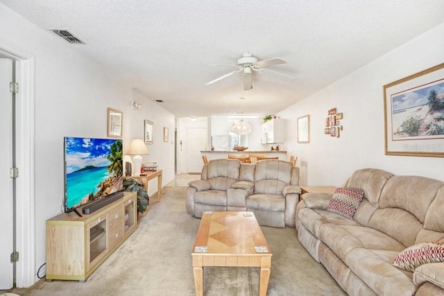 carpeted living room with ceiling fan and a textured ceiling