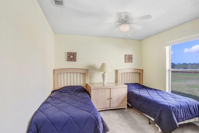 carpeted bedroom with ceiling fan and a textured ceiling