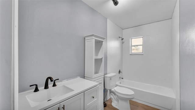 full bathroom with hardwood / wood-style flooring, vanity, tub / shower combination, and toilet