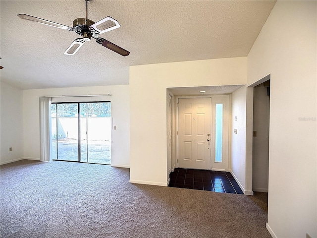 foyer entrance with ceiling fan, a textured ceiling, and dark colored carpet