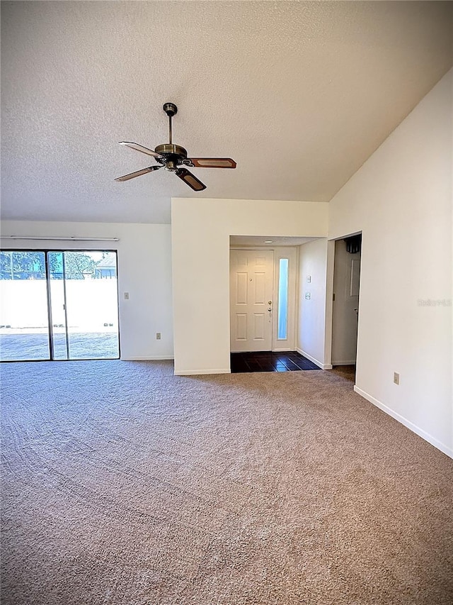 carpeted empty room with vaulted ceiling, ceiling fan, and a textured ceiling