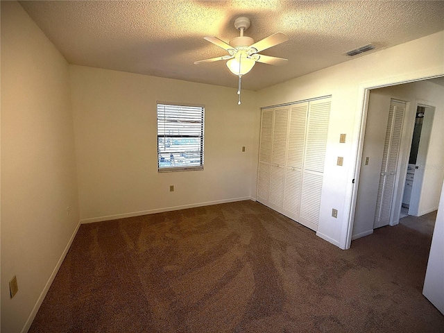 unfurnished bedroom featuring dark colored carpet, ceiling fan, a textured ceiling, and a closet