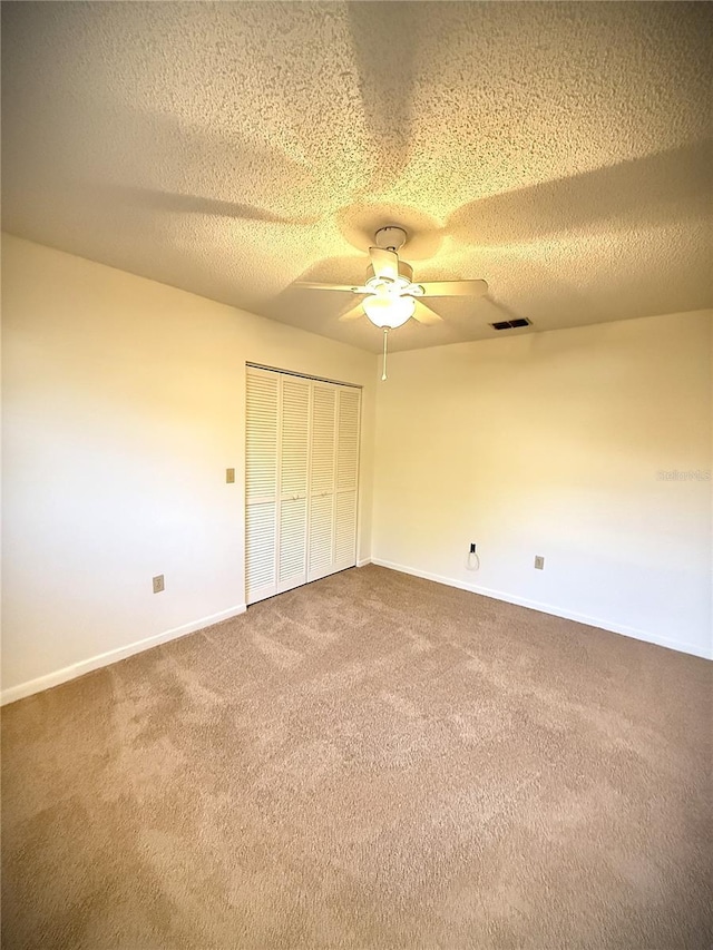 unfurnished bedroom with ceiling fan, a closet, carpet, and a textured ceiling