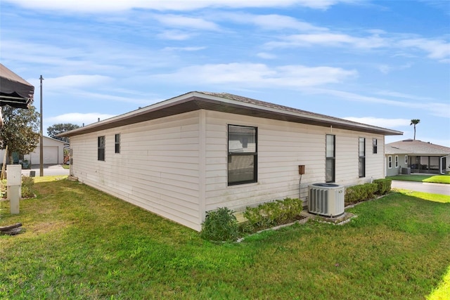 view of side of property with central AC and a lawn