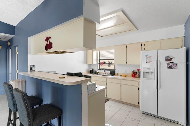 kitchen with sink, a breakfast bar area, white fridge with ice dispenser, kitchen peninsula, and cream cabinets