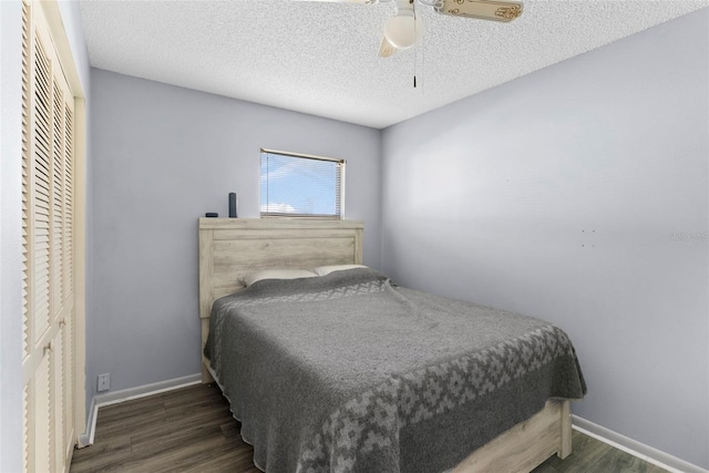 bedroom featuring dark hardwood / wood-style flooring, ceiling fan, a closet, and a textured ceiling