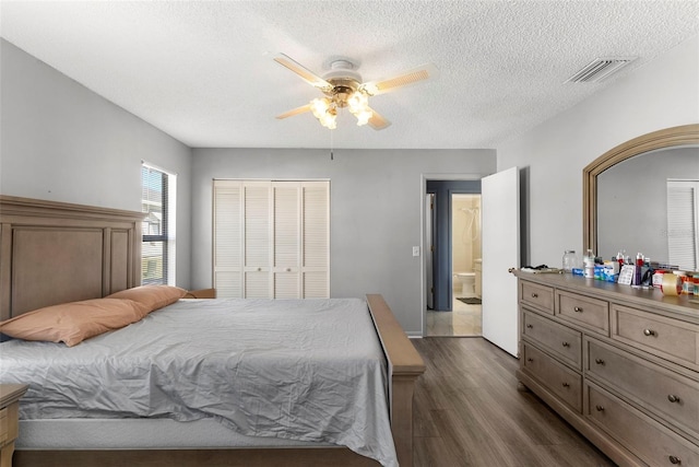 bedroom with ceiling fan, dark hardwood / wood-style floors, a textured ceiling, and a closet