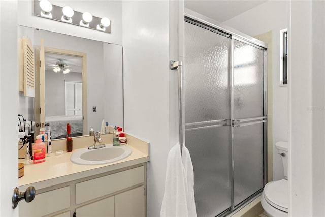 bathroom with ceiling fan, vanity, toilet, and a shower with door