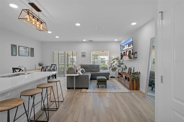 living room featuring sink and light hardwood / wood-style flooring