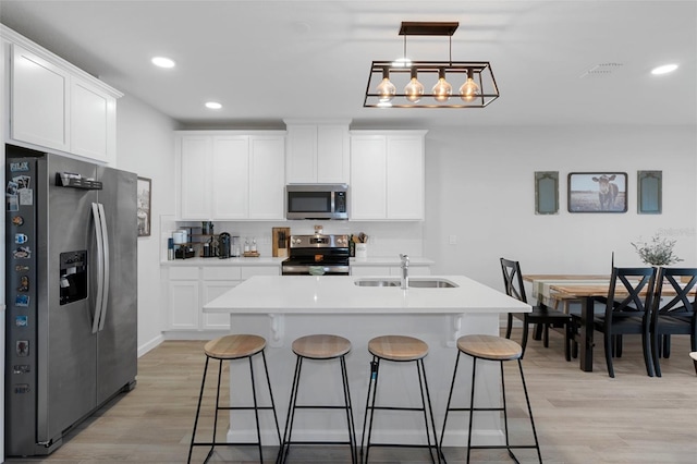 kitchen featuring stainless steel appliances, sink, pendant lighting, and white cabinets