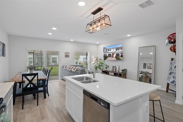 kitchen with sink, white cabinetry, a center island with sink, stainless steel dishwasher, and pendant lighting