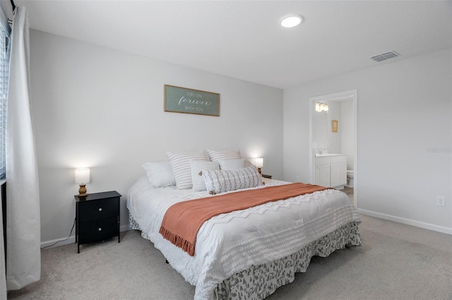 bedroom with light colored carpet and ensuite bath