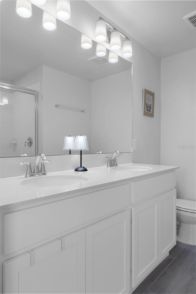 bathroom featuring vanity, hardwood / wood-style flooring, toilet, and walk in shower