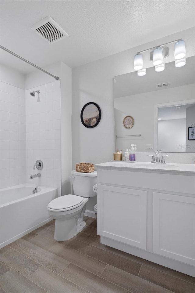 full bathroom featuring vanity, a textured ceiling, toilet, and tiled shower / bath