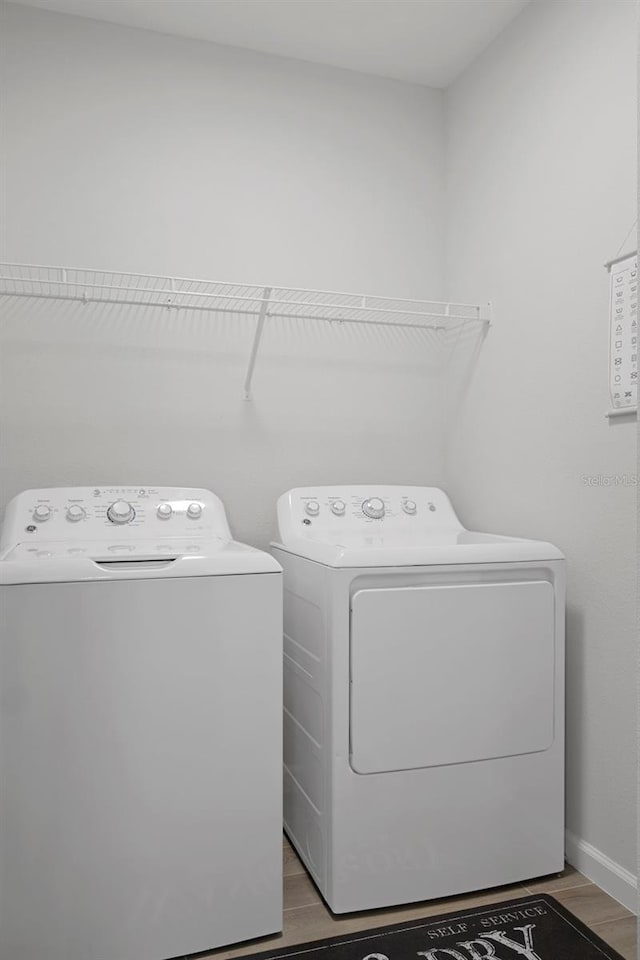 laundry room with independent washer and dryer and light hardwood / wood-style flooring