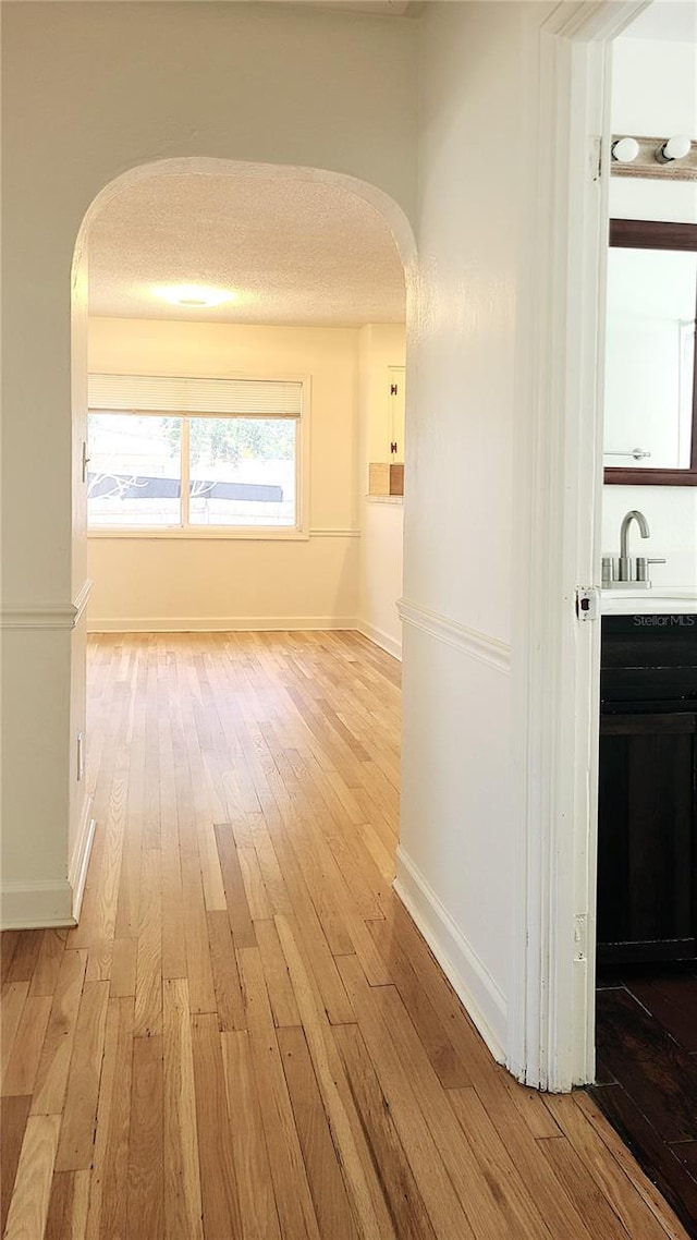 hall featuring sink, light hardwood / wood-style flooring, and a textured ceiling