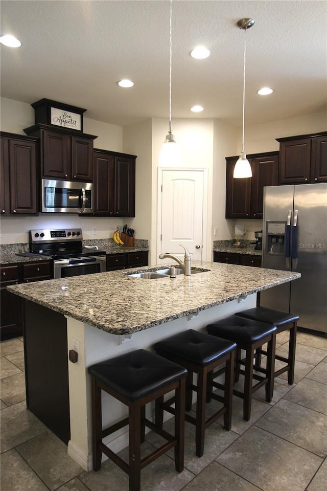 kitchen featuring sink, a center island with sink, a kitchen breakfast bar, and appliances with stainless steel finishes