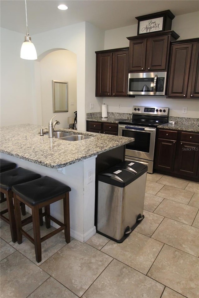 kitchen with appliances with stainless steel finishes, a breakfast bar, sink, and hanging light fixtures