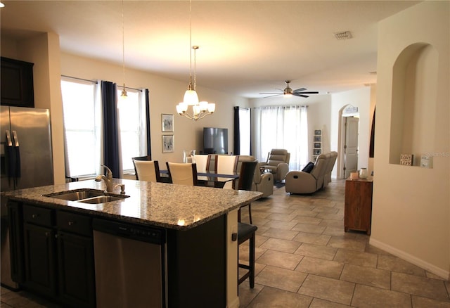 kitchen with appliances with stainless steel finishes, a breakfast bar, an island with sink, sink, and hanging light fixtures