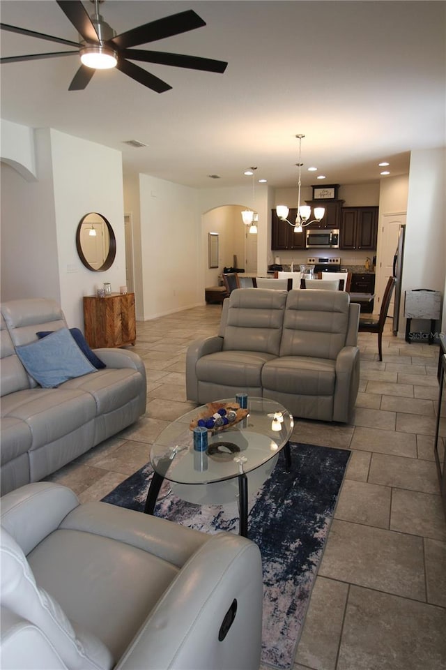 living room featuring ceiling fan with notable chandelier