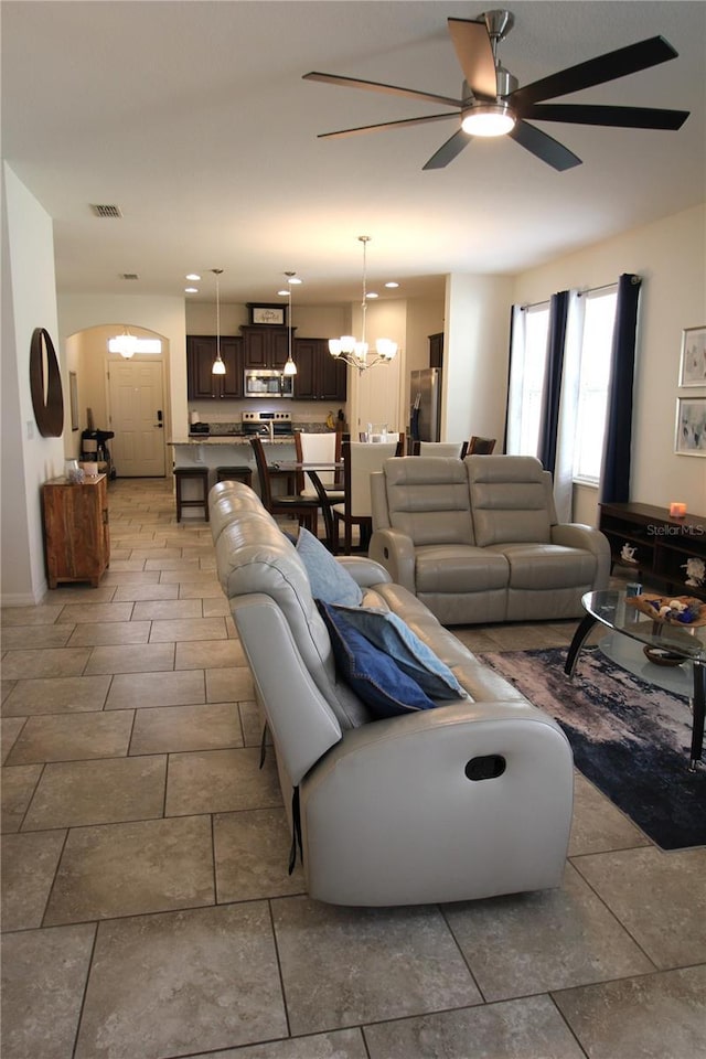 tiled living room featuring ceiling fan with notable chandelier