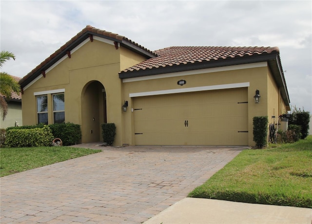 mediterranean / spanish-style home featuring a garage and a front lawn