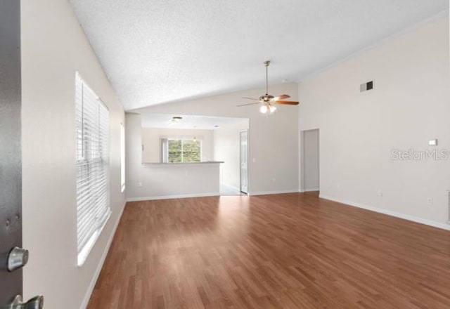 unfurnished living room with lofted ceiling, hardwood / wood-style floors, a textured ceiling, and ceiling fan