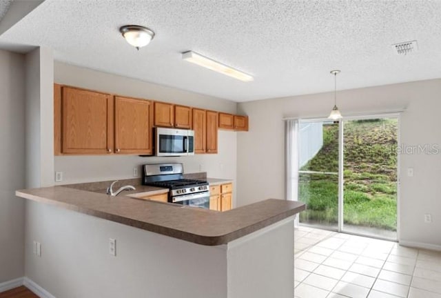 kitchen with pendant lighting, appliances with stainless steel finishes, kitchen peninsula, and a textured ceiling