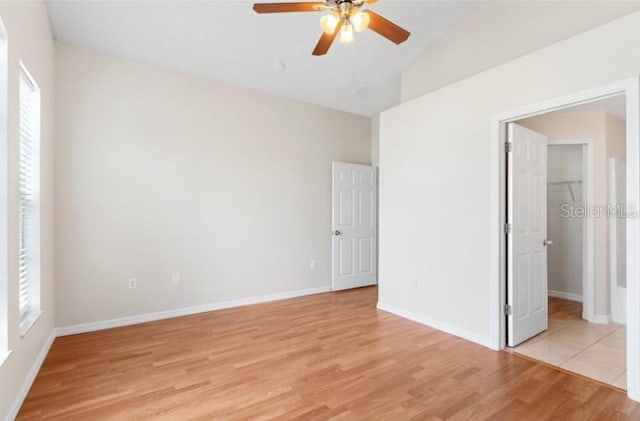 unfurnished bedroom with lofted ceiling, a spacious closet, ceiling fan, and light wood-type flooring