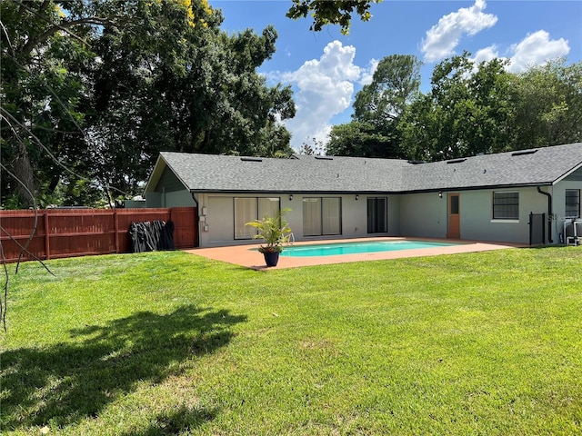 rear view of property with a yard, a fenced in pool, and a patio area