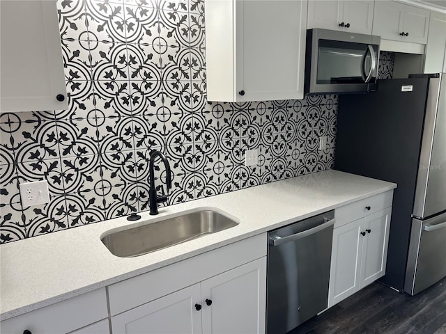 kitchen featuring appliances with stainless steel finishes, sink, white cabinets, decorative backsplash, and dark wood-type flooring