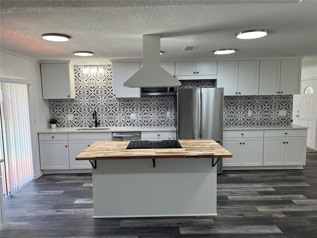 kitchen featuring island exhaust hood, wood counters, sink, and white cabinets