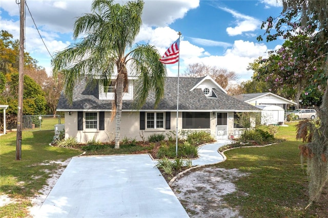 cape cod-style house with a shingled roof, a front yard, a gate, and fence