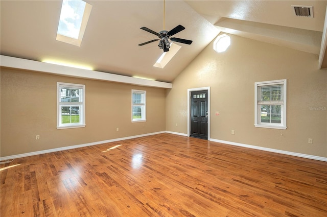 spare room featuring ceiling fan, a skylight, visible vents, baseboards, and light wood finished floors