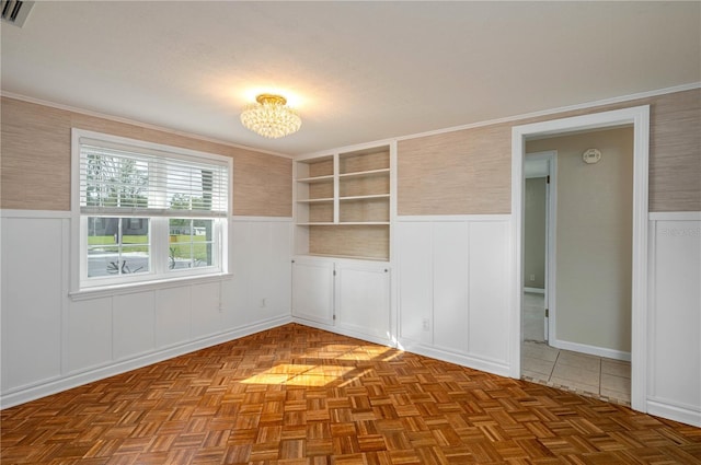 unfurnished room featuring visible vents, ornamental molding, and wainscoting