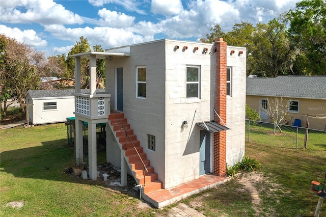 exterior space with an outdoor structure, concrete block siding, fence, a lawn, and a storage unit