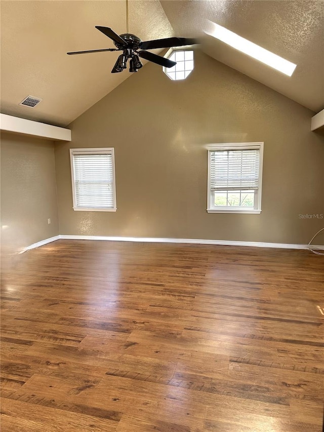 unfurnished room featuring a healthy amount of sunlight, visible vents, a textured ceiling, and wood finished floors