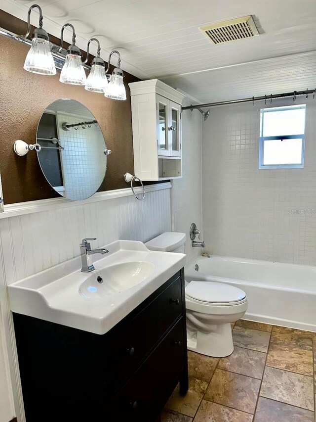 bathroom with visible vents, toilet, a wainscoted wall, vanity, and washtub / shower combination