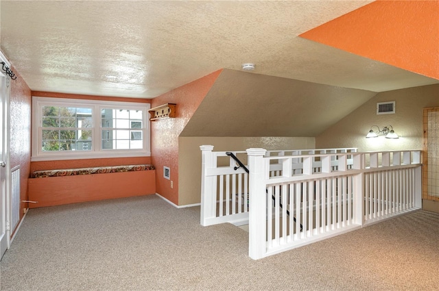 additional living space with carpet floors, visible vents, and a textured ceiling