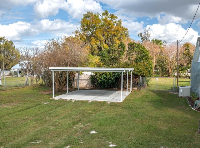 view of yard with driveway, fence, a patio, and a detached carport