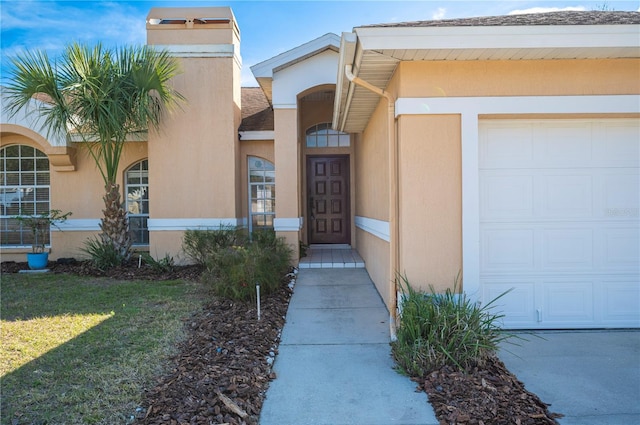 doorway to property with a garage and a lawn