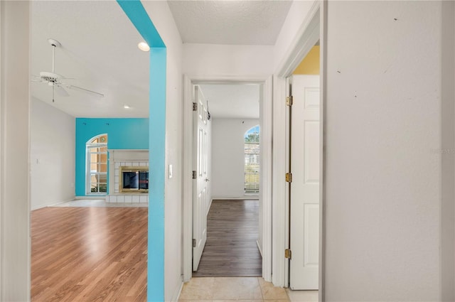 hall with light hardwood / wood-style floors and a textured ceiling