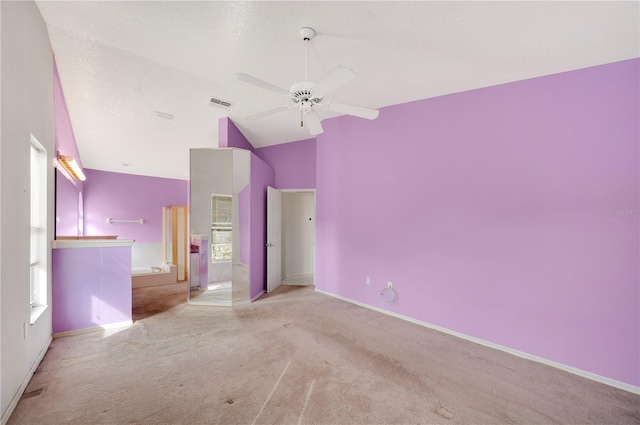 unfurnished bedroom featuring vaulted ceiling, light colored carpet, ceiling fan, and a textured ceiling