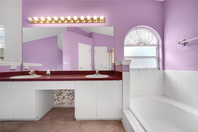 bathroom featuring vanity and tiled tub