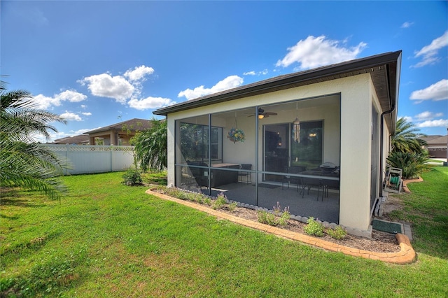 back of property with ceiling fan, a sunroom, and a lawn