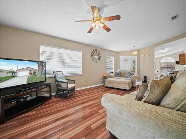 living room with wood-type flooring, lofted ceiling, a wealth of natural light, and a textured ceiling