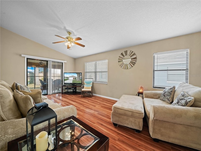 living room featuring hardwood / wood-style flooring, plenty of natural light, vaulted ceiling, and a textured ceiling