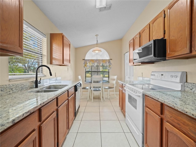 kitchen with appliances with stainless steel finishes, decorative light fixtures, sink, light tile patterned floors, and light stone counters