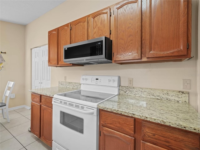 kitchen featuring light stone counters, light tile patterned floors, and electric range