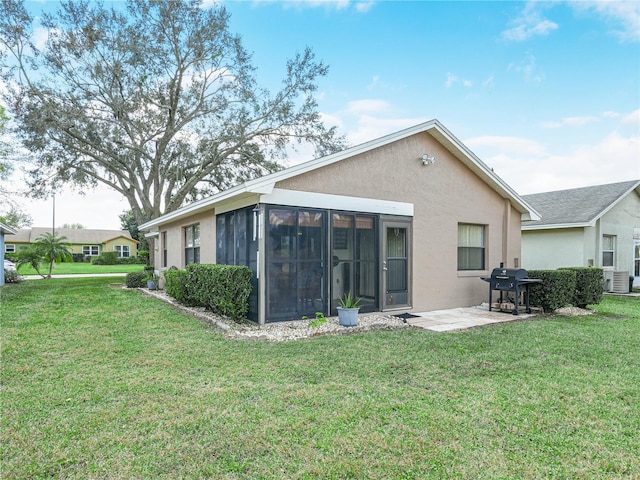 back of house featuring a yard, a patio area, and a sunroom